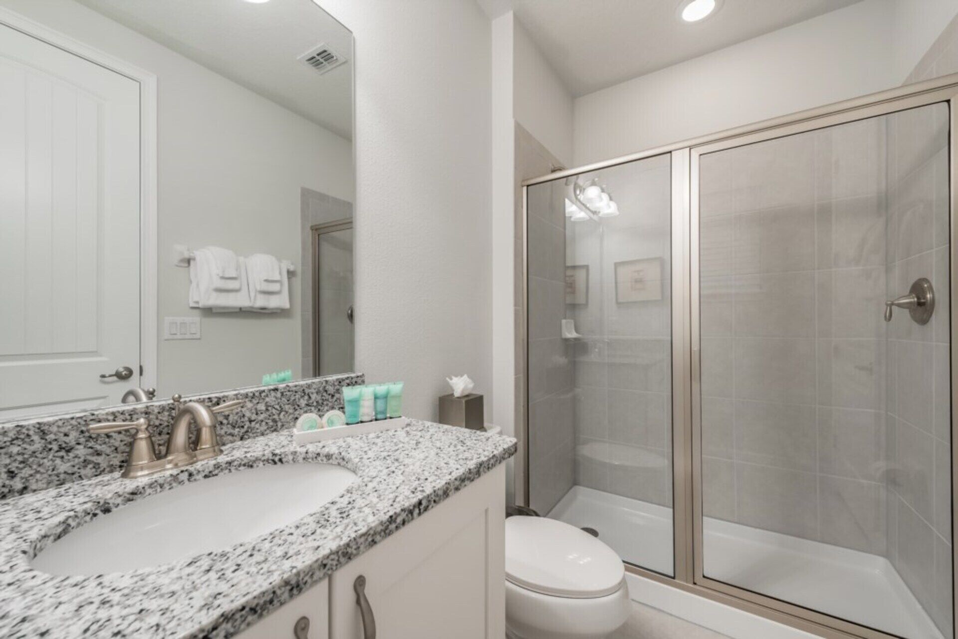 Un bagno con lavabo su piano in granito, un WC e doccia vetrata.