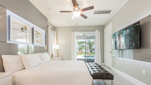 A modern bedroom with a large bed, a ceiling fan, a TV, and a view of a swimming pool. - Beautiful Villa With Private Pool, Close to Disney, Orlando Villa 2942 (Kissimmee)