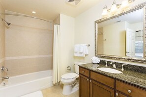A bathroom with a bathtub, toilet, vanity with a sink, and a large mirror. - Luxury 3 Bedroom Condo on Reunion Resort, Orlando Condo 3501 (Kissimmee)
