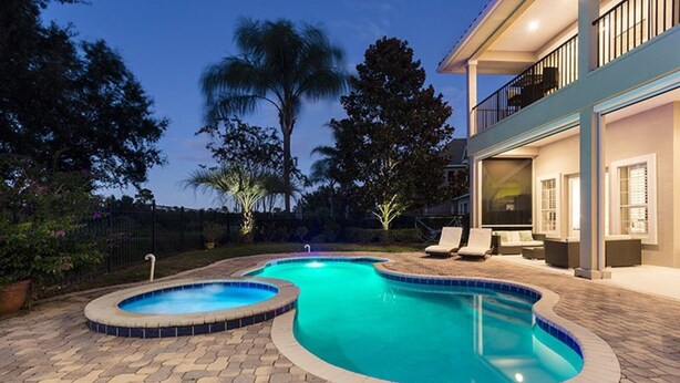 A swimming pool with a curved design, surrounded by a paved patio. - Rent a Luxury Villa on Reunion Resort, Minutes From Disney, Orlando Villa 3539 (Kissimmee)