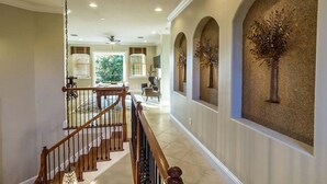 A spacious interior with a high ceiling, a staircase, and a view of the outdoors. - Rent a Luxury Villa on Reunion Resort, Minutes From Disney, Orlando Villa 3539 (Kissimmee)