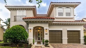 A two-story house with a tiled roof, a front entrance with a door, and two garage doors. - Rent a Luxury Villa on Reunion Resort, Minutes From Disney, Orlando Villa 3539 (Kissimmee)