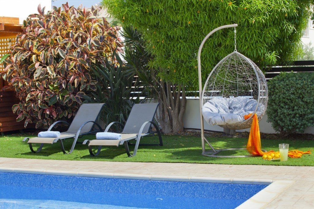 Ein Poolbereich mit zwei Liegestühlen, einer Hängematte und einem Tisch mit Getränken und Zitronen.