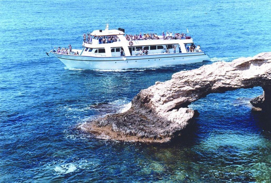 A boat with passengers, navigating near a rocky coastline.