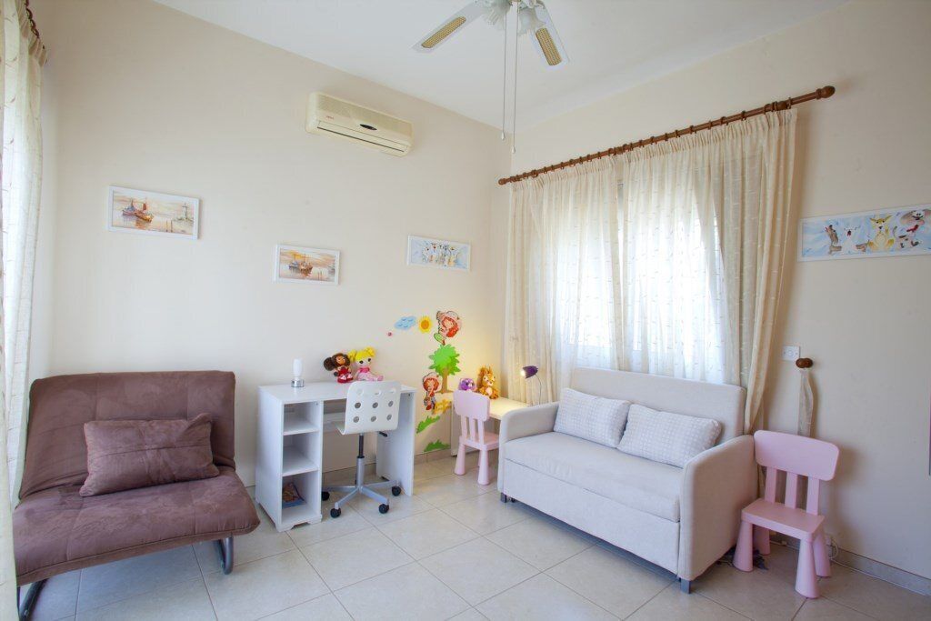 A living room with a brown sofa, a white sofa, a desk with a chair, and a pink chair.