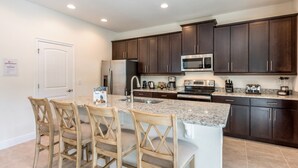 A modern kitchen with dark wood cabinets, stainless steel appliances, and a granite countertop. - Villa in Encore Resort at Reunion 3438 (Kissimmee)