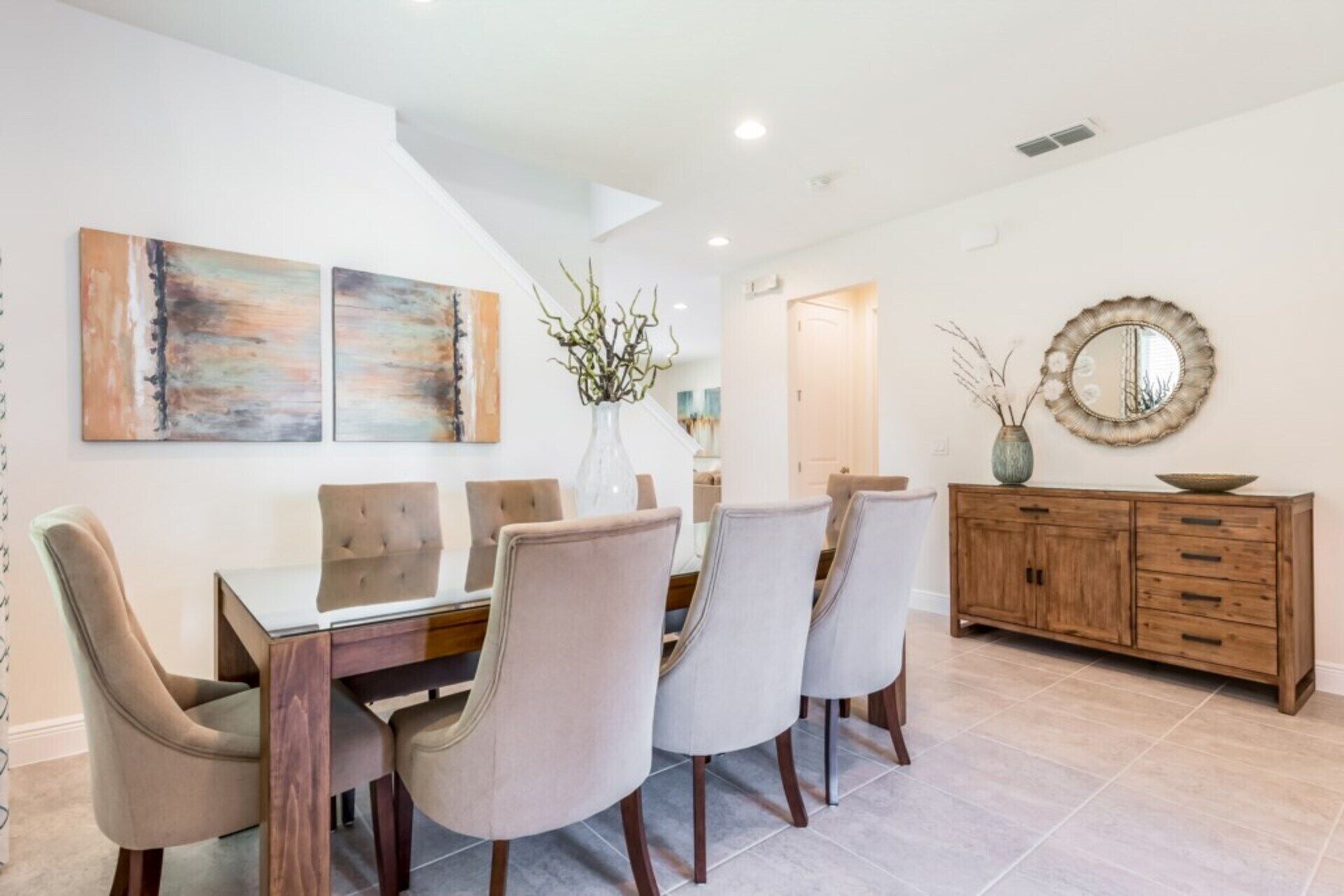 Un coin repas avec une table et des chaises en bois, un buffet en bois et deux tableaux abstraits accrochés au mur.