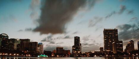 A nighttime cityscape with high-rise buildings reflected in calm water.