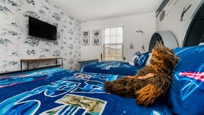 A bedroom with Star Wars-themed bedding, a flat-screen TV, and Star Wars decorations on the walls.