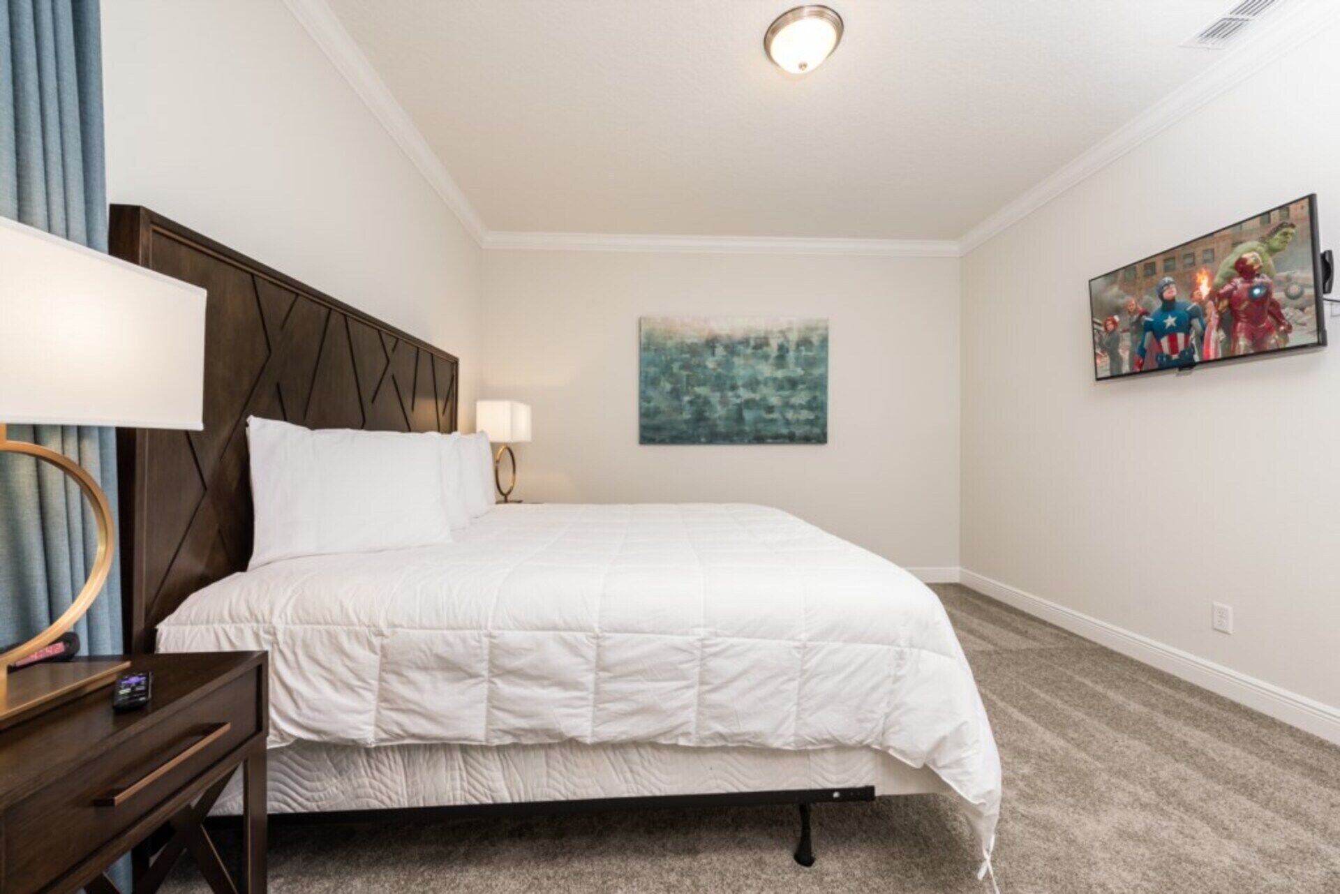 A hotel room with a bed, a nightstand, a lamp, a painting, and a ceiling light.