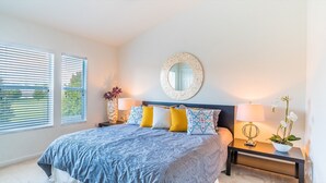 A bedroom with a bed, bedside tables, a mirror, and a window with blinds.