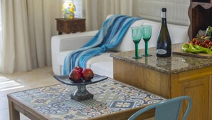 Une cuisine avec une table carrelée, une bouteille de vin et un panier de fruits.