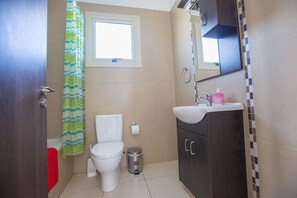 A bathroom with a toilet, sink, and cabinet.