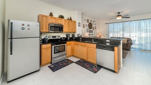 A modern kitchen with wooden cabinets, stainless steel appliances, and a black countertop. - Luxury 3 Bedroom House on Windsor Hills Resort, Orlando House 1902 (Kissimmee)