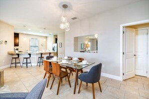 A dining area with a glass table set for six, surrounded by wooden chairs.