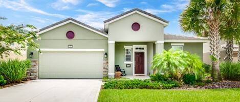 A two-story house with a garage, a front porch, and a well-maintained lawn.
