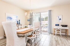 A dining area with a wooden table, white chairs, and a chandelier. There is a sliding glass door leading to an outdoor patio. - Rent a Luxury Villa on Champions Gate Resort, Minutes From Disney, Orlando Villa 2988 (Davenport)