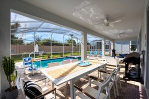 A covered outdoor area with a pool, lounge chairs, and a barbecue grill. - Rent a Luxury Villa on Champions Gate Resort, Minutes From Disney, Orlando Villa 2988 (Davenport)