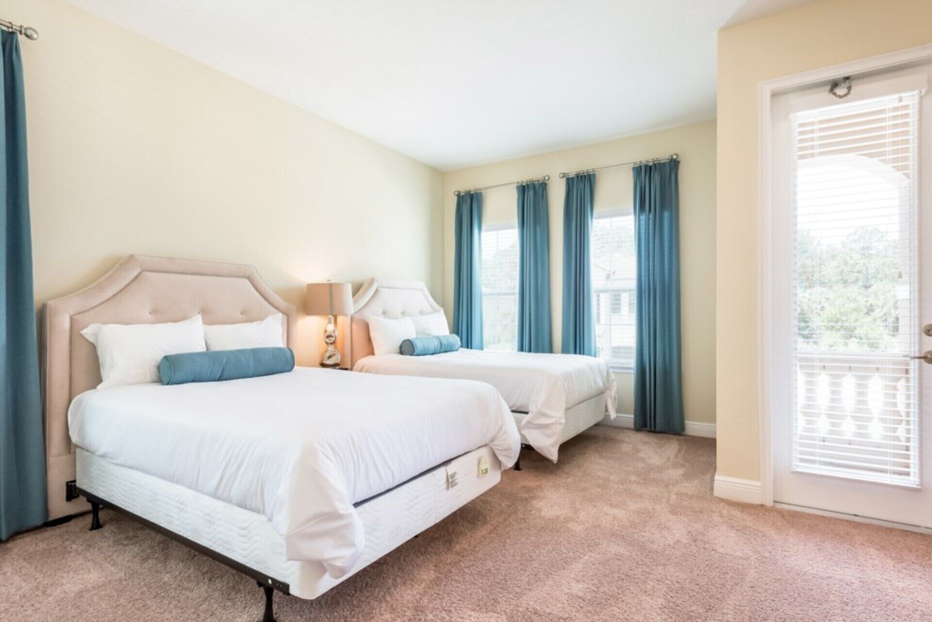 A bedroom with two beds, a nightstand, and a window with curtains.