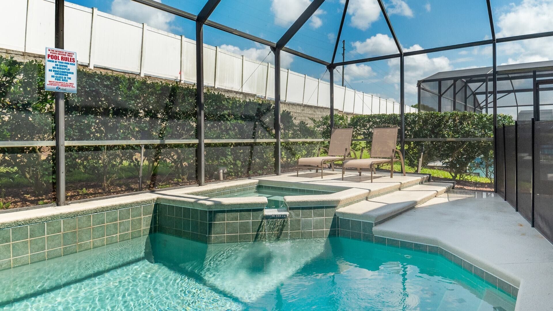 An indoor swimming pool with tiled walls, a glass enclosure, and lounge chairs.