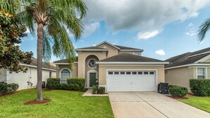 A single-story house with a beige facade, a central arched window, and a garage. - Luxury 5 Bedroom Villa on Windsor Palms Resort, Orlando Villa 3310 (Kissimmee)