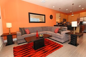 A modern living room with a grey sofa, red and patterned cushions, a black coffee table, and a red shag rug.