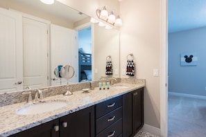 A bathroom with two sinks, a large mirror, and a vanity with drawers.