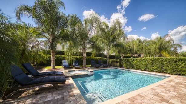 A rectangular swimming pool with a hot tub, surrounded by palm trees and lounge chairs. - Luxury 8 Bedroom Villa on Encore Resort at Reunion, Orlando Villa 1987 (Kissimmee)