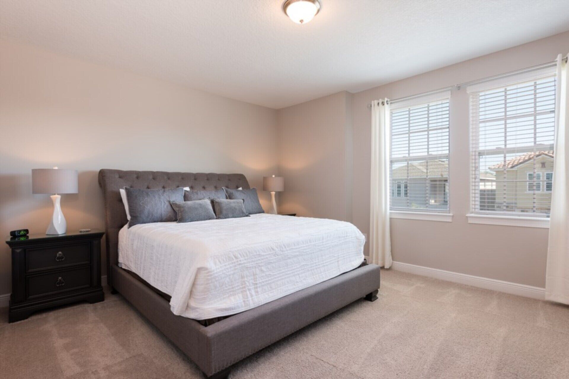 A bedroom with a large bed, two bedside tables, and a window with blinds.
