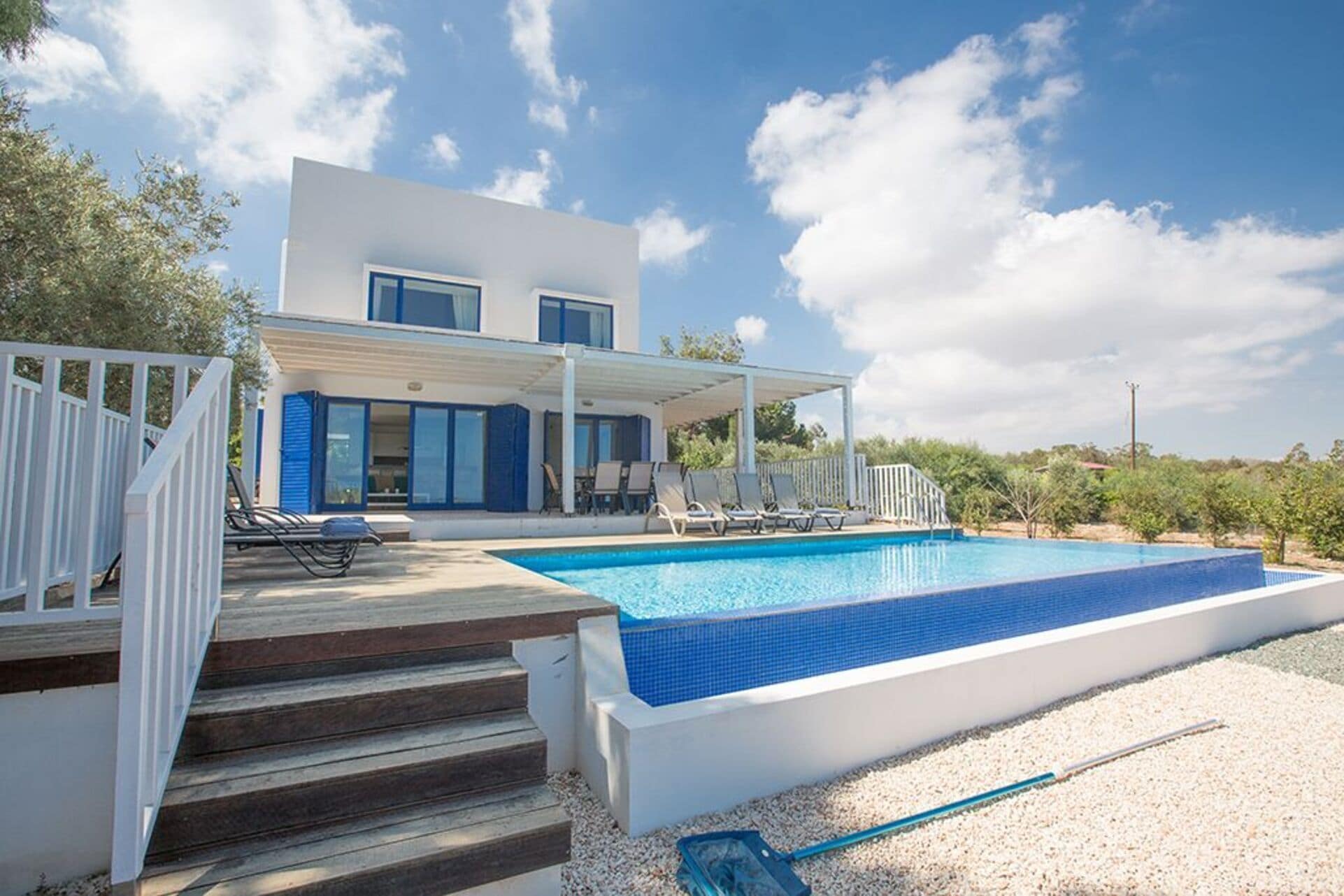 A modern two-story house with a swimming pool, outdoor seating, and a covered patio area.