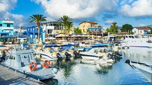 Un port de plaisance avec des bateaux amarrés, une promenade en bord de mer et des bâtiments dotés de balcons donnant sur l’eau.