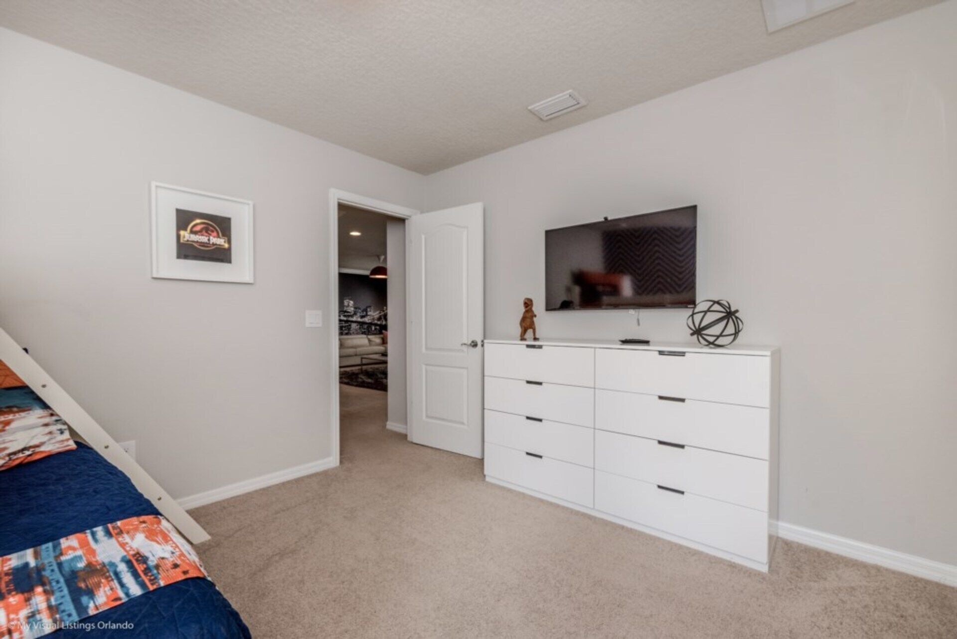 A bedroom with a bed, a dresser, a television, and a framed picture on the wall.