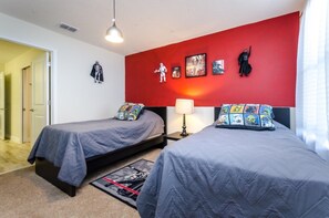Een kamer met twee eenpersoonsbedden, een rode accentmuur en decoraties met Star Wars thema.