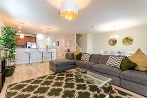 Een moderne woonkamer met een modulaire bank, een glazen salontafel en een vloerkleed met patroon.