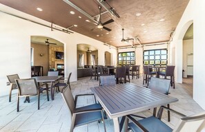A spacious indoor dining area with multiple tables and chairs, a ceiling fan, and large windows providing natural light. - Beautiful Villa With Private Pool, Close to Disney, Orlando Villa 1266 (Kissimmee)