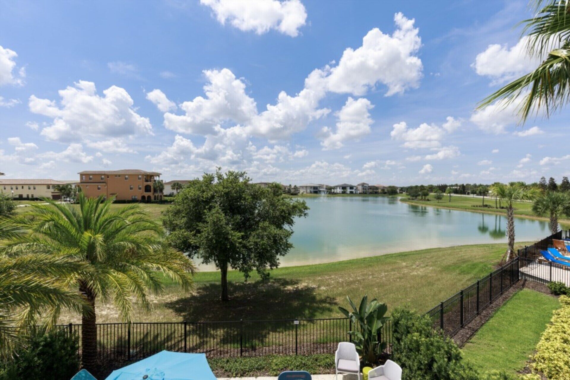 A view of a lake with a building in the background, surrounded by greenery and a clear sky.