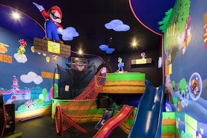 En lekplats för barn med rutschkanor, en basketkorg och figurer av Mario och Luigi.