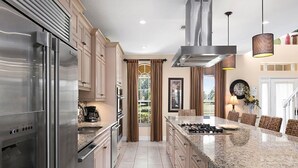 A modern kitchen with stainless steel appliances, a large island, and a dining area with a chandelier. - Luxury 9 Bedroom Villa on Osceola County, Orlando Villa 3569 (Kissimmee)