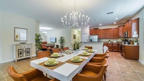 A spacious dining area with a long table set for six, surrounded by orange chairs.