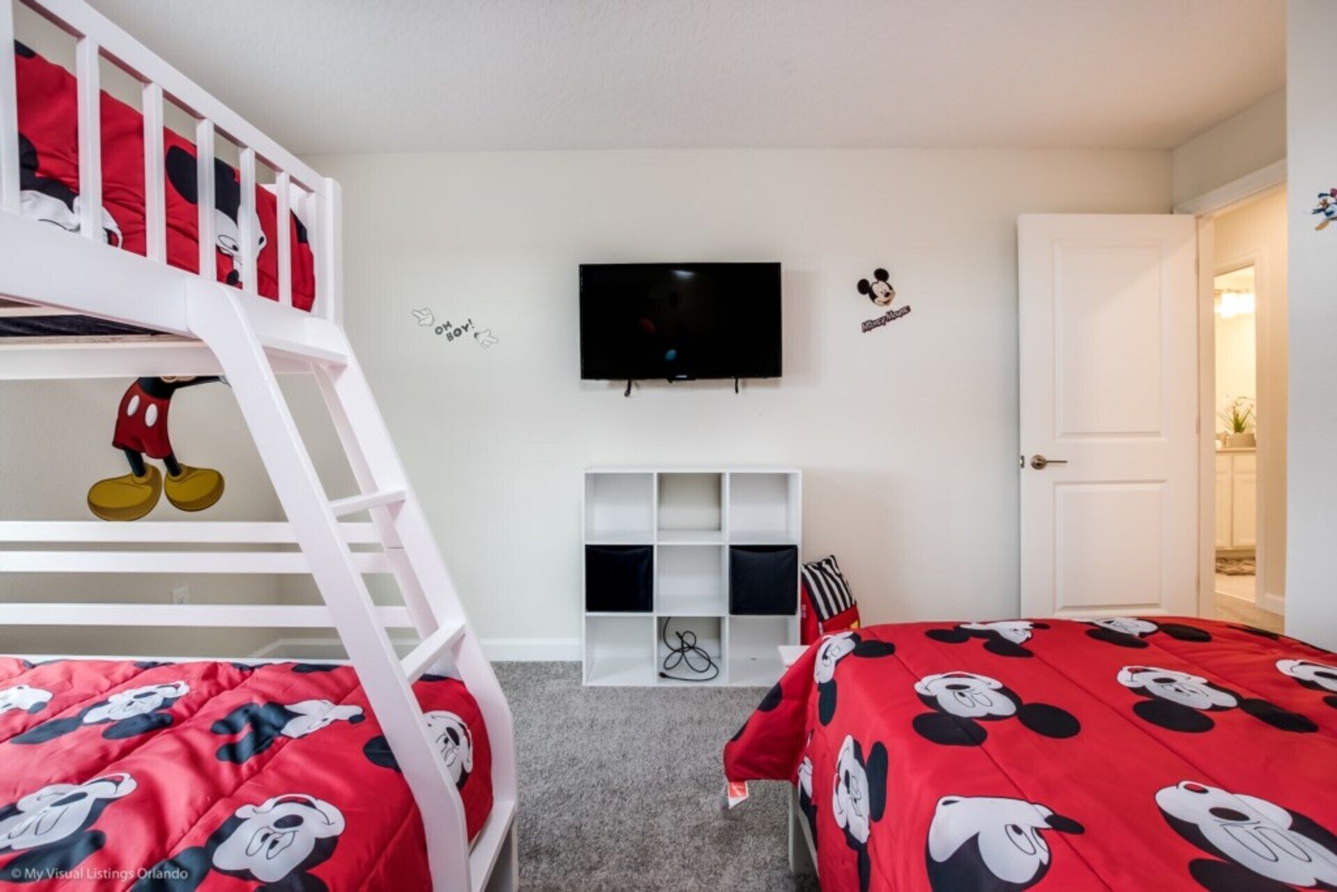 A child's bedroom with bunk beds, a TV, and Mickey Mouse decorations.