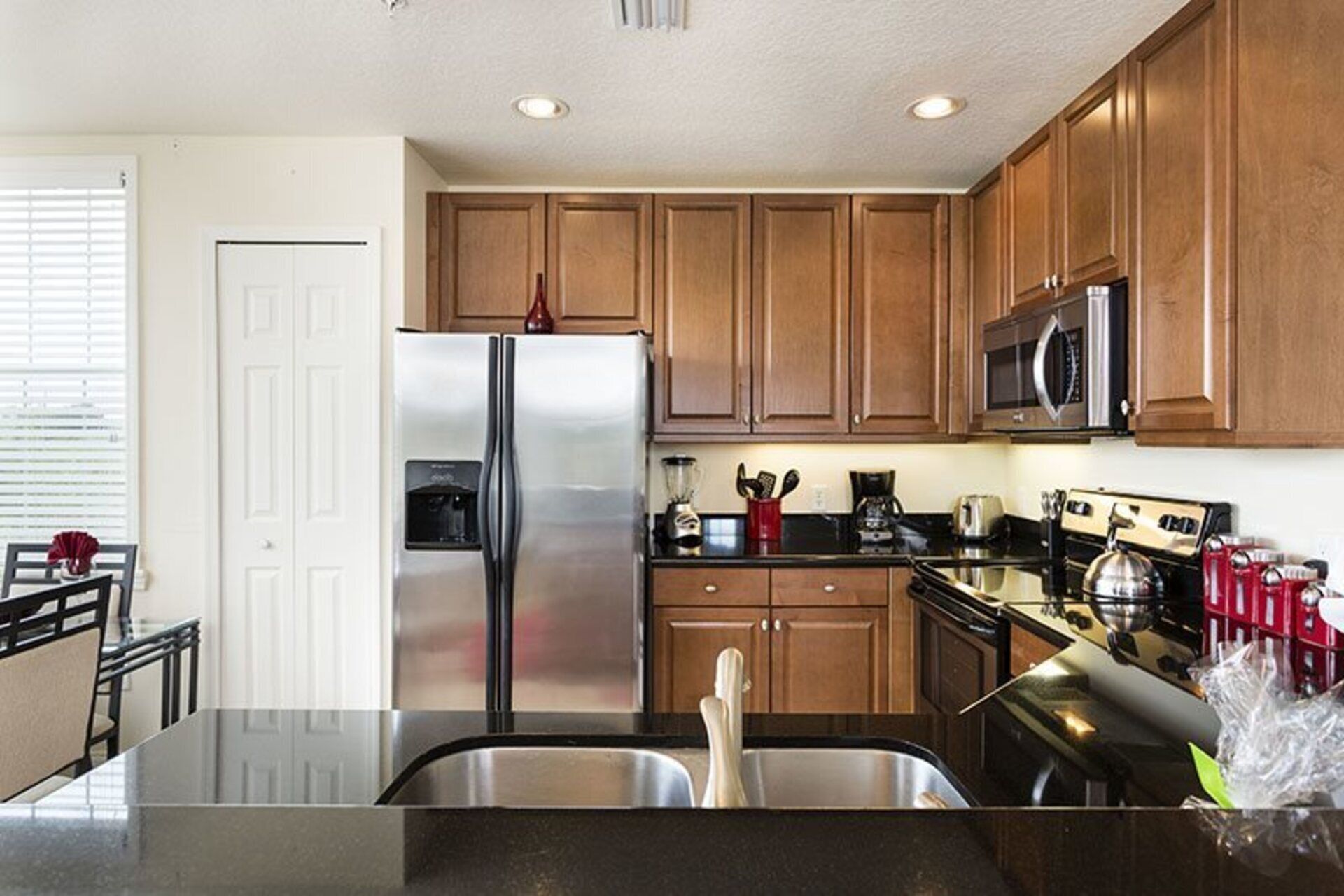 A modern kitchen with wooden cabinets, stainless steel appliances, and a black countertop.