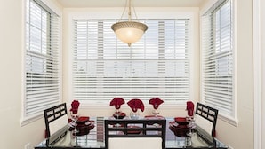 Un espace repas avec une table en verre, des chaises noires et des touches de couleur rouge.