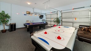 A room with a pool table, foosball table, and a couch.
