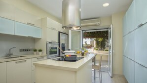 Une cuisine moderne dotée d’un îlot central, d’appareils électroménagers intégrés et offrant une vue sur l’extérieur.