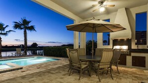 An outdoor patio with a pool, dining table, chairs, and a ceiling fan.