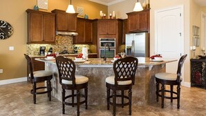 A kitchen with a central island, wooden cabinets, and a stainless steel refrigerator.