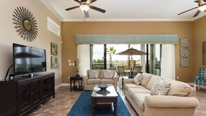 A living room with a TV, sofas, a coffee table, and a ceiling fan.