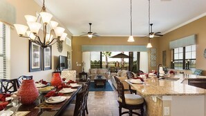 A spacious kitchen with a central island, pendant lighting, and a ceiling fan.