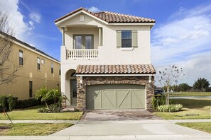 A two-story house with a stone facade, a balcony, and a garage. - Rent a Luxury Villa on Reunion Resort, Minutes From Disney, Orlando Villa 3556 (Kissimmee)