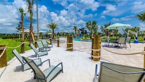 A poolside area with lounge chairs, umbrellas, and palm trees under a clear sky. - Rent a Luxury Townhome on Storey Lake Resort, Minutes From Disney, Orlando Townhome 3224 (Kissimmee)